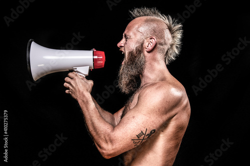 Angry male viking screaming while holding megaphone against black background
