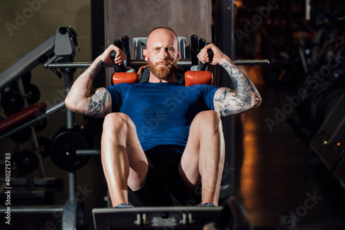 Man doing quadriceps exercise on hack squat machine at gym photo