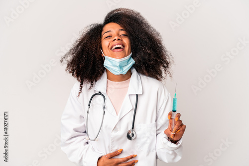 Young african american curly doctor woman holding a syringe laughing and having fun. © Asier