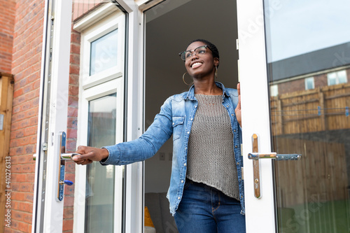 Smiling woman opening house doors