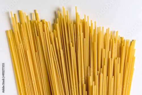 A spread of dry raw spaghetti on a white background