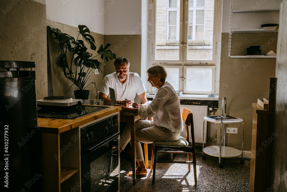 Smiling businessman discussing with mature female colleague in office Smiling businessman discussing with mature female colleague in office