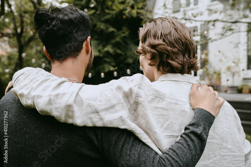 Rear view of man with arm around on male friend in backyard photo