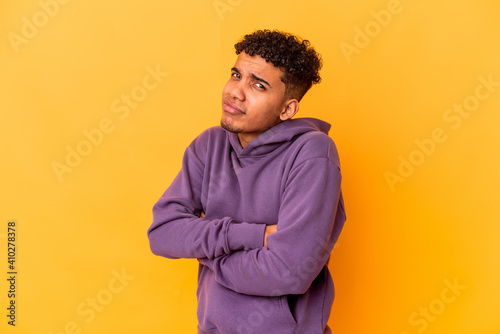 Young african american curly man isolated on purple suspicious, uncertain, examining you.