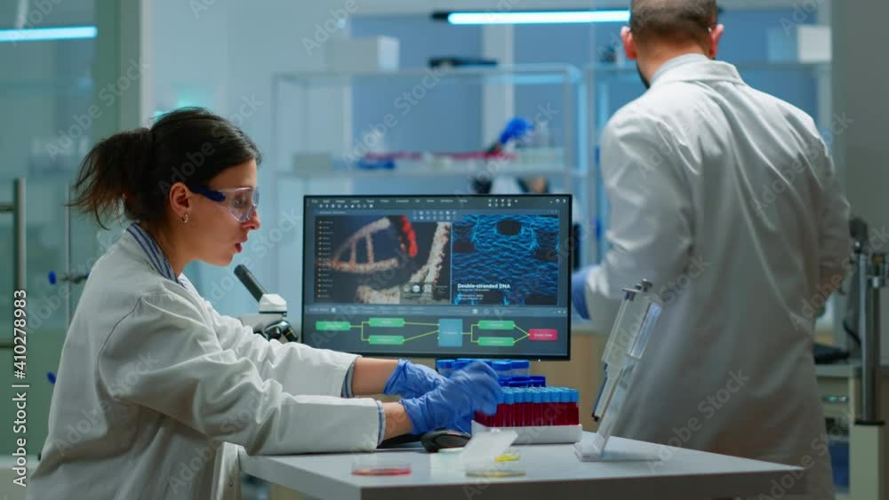 Team of microbiology scientists discussing about virus development in modern equpped laboratory using computer analysing test blood samples and develop vaccine, drugs and antibiotics against covid-19.