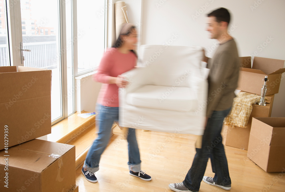 Man and woman carrying chair in new house Man and woman carrying chair in new house