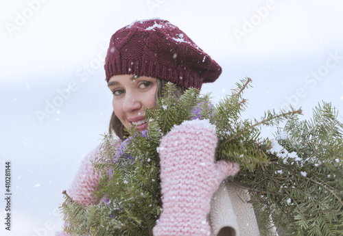 Portrait of young woman wearing knit hat, gloves and scarf an carrying fir wreath photo