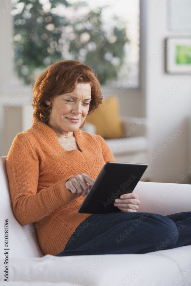 Woman sitting on sofa using digital tablet Woman sitting on sofa using digital tablet