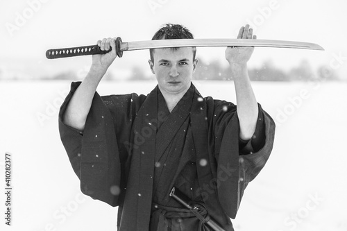 samurai warrior stands with sword and staff in the middle of an empty winter field