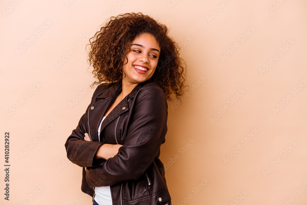 Young african american woman isolated on beige background smiling confident with crossed arms. Young african american woman isolated on beige background smiling confident with crossed arms.