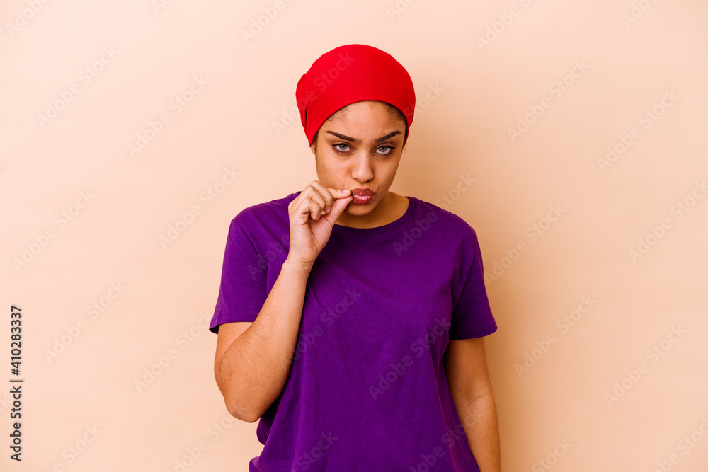 Young african american woman isolated on beige background with fingers on lips keeping a secret.