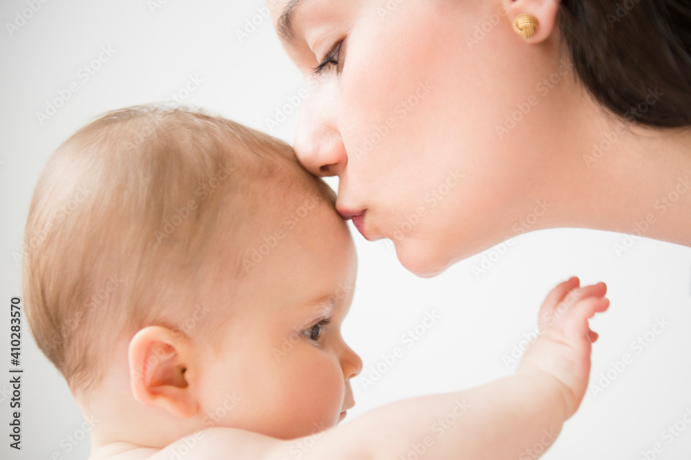 Side view of mother kissing her baby daughter (6-11 months) Side view of mother kissing her baby daughter (6-11 months)