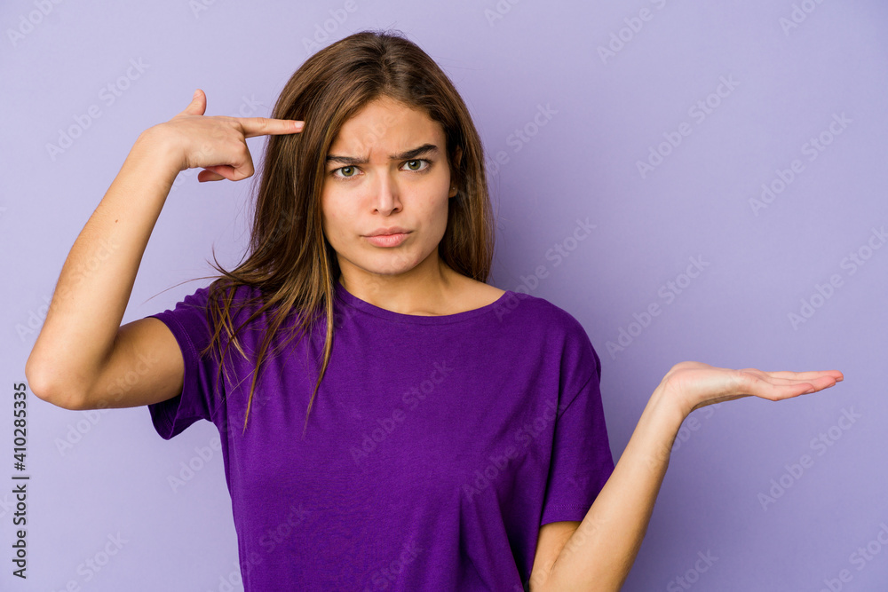 Young skinny caucasian girl teenager on purple background holding and showing a product on hand. Young skinny caucasian girl teenager on purple background holding and showing a product on hand.