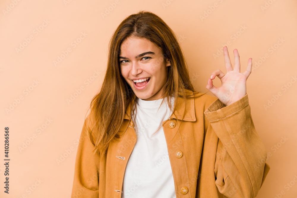 Young skinny caucasian teenager girl winks an eye and holds an okay gesture with hand. Young skinny caucasian teenager girl winks an eye and holds an okay gesture with hand.