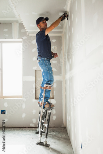 Drywall worker on stilts working on drywall joints photo
