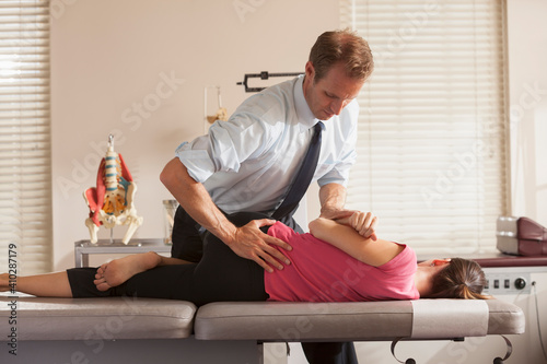 Woman lying on side getting adjusted by chiropractor
