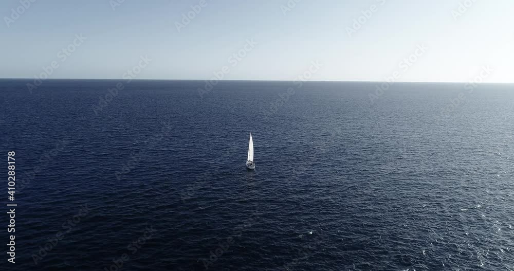 Aerial view of a sailboat sailing in the middle of the Mediterranean Sea. We can see the boat and the water all over the horizon 4K Aerial view of a sailboat sailing in the middle of the Mediterranean Sea. We can see the boat and the water all over the horizon 4K
