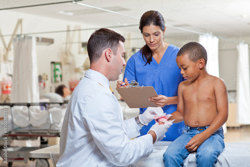 Doctors applying bandage on boy's (4-5) hand Doctors applying bandage on boy's (4-5) hand