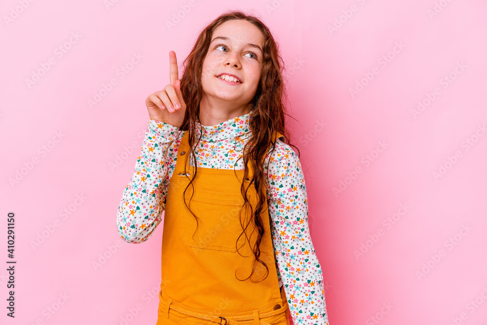 Little caucasian girl isolated on pink background indicates with both fore fingers up showing a blank space. Little caucasian girl isolated on pink background indicates with both fore fingers up showing a blank space.
