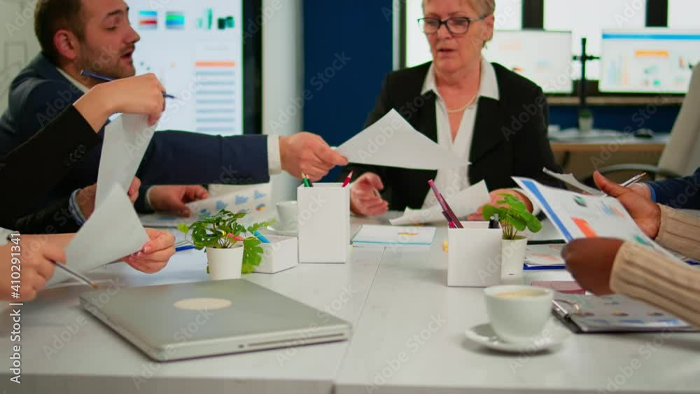 Confident company manager giving working tasks to diverse teamworkers analysing paperwork with graphs sitting in start up office. Multiethnic team discussing project ideas at brainstorming meeting Confident company manager giving working tasks to diverse teamworkers analysing paperwork with graphs sitting in start up office. Multiethnic team discussing project ideas at brainstorming meeting