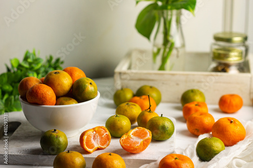 Jeruk Santang or Santang Mandarin oranges, on white bowl with white wooden background. Copy space for text. 