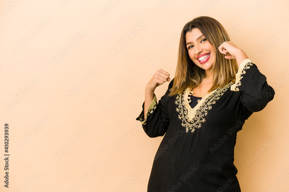 Young indian woman wearing traditional clothes isolated raising fist after a victory, winner concept.