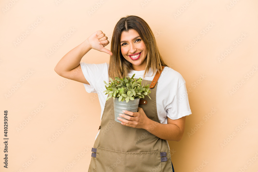 Young indian gardener woman holding a plant isolated feels proud and self confident, example to follow. Young indian gardener woman holding a plant isolated feels proud and self confident, example to follow.