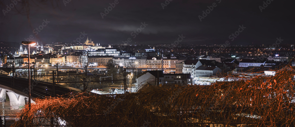 .street lights and pedestrian walkway in the park and in the background a view of the city of prague and prague castle at night in the center of prague in the czech republic