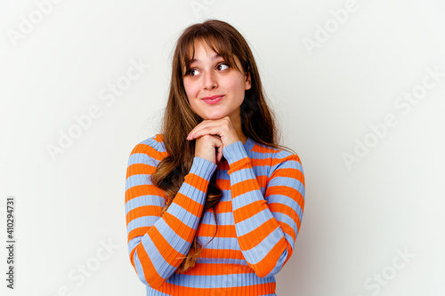 Young caucasian cute woman isolated on white background keeps hands under chin, is looking happily aside. © Asier