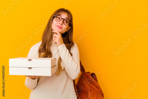 Young student caucasian woman holding pizzas over isolated background looking sideways with doubtful and skeptical expression.