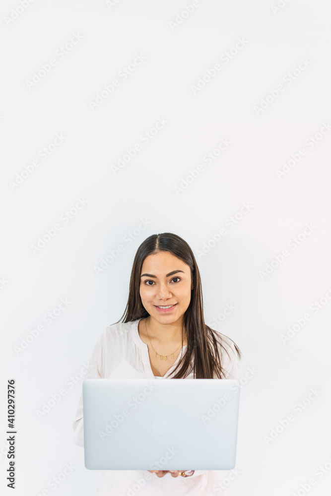 Pretty young woman looks sitting on the floor with laptop looking at the camera with white background Pretty young woman looks sitting on the floor with laptop looking at the camera with white background