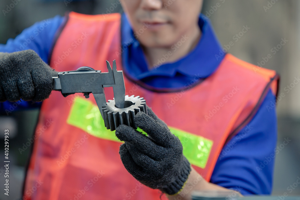 male worker checking  dimensions of the metal workpiece with a caliper.worker checking gears with a caliper. worker in factory on the machine.