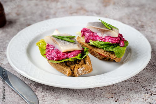 Close up of two homemade herring sandwiches with beet and green leaves on white plate. Herring is a saurce of omega 3 fats healthy for brain and mental clarity. Brain food concept. Home cooking