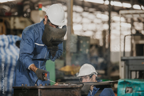 Industrial Worker at the factory welding. Workers wearing industrial uniforms and Welded Iron Mask at factory welding plants