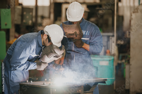 Industrial Worker at the factory welding. Workers wearing industrial uniforms and Welded Iron Mask at factory welding plants