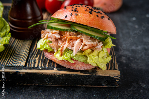 Close up of fish burger with pink bun and salmon on black. Omega 3 fats healthy for brain. Home cooking photo