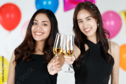 Two young and beautiful sexy Asian girls holding glass of wine drinking in party with fun and happieness