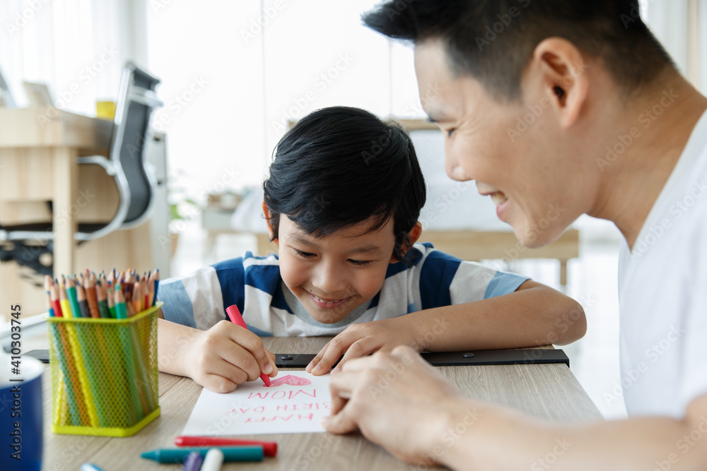 Asian family father and daughter is teaching my children to write greeting cards for mom with little son on chair at home in mother day... Asian family father and daughter is teaching my children to write greeting cards for mom with little son on chair at home in mother day...