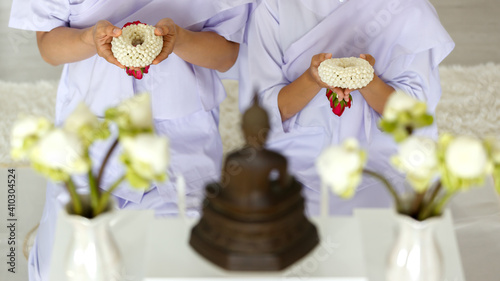 Foto Man and woman Buddhist in white dress sitting  in front of set of altar table and paying homage to buddha image