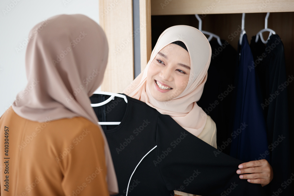 Two Asian Muslim women selecting clothes together with happiness