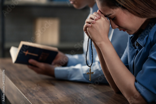 Woman are making a wish before Jesus, holding both hands and man are reading the Bible to make wishes and remember the Lord. Concept believe faith prayer..