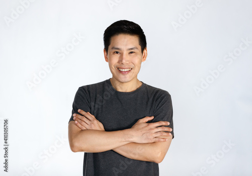 Portrait of a young and handsome Asian man folding arms with self-confident posing