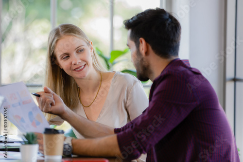 Two businesspeople, man and woman, working together in a modern office in an intimate manner. Idea for teamwork and good business colleagues