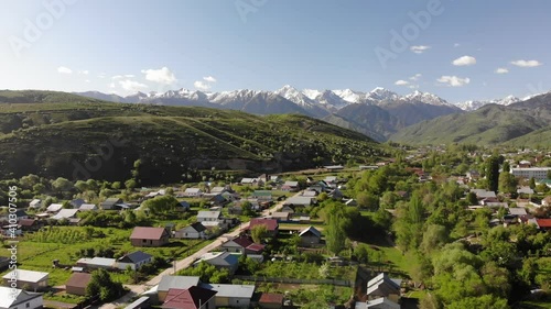 Mountain village from the air. Beautiful panorama of the village and snowy peaks. Spring landscape