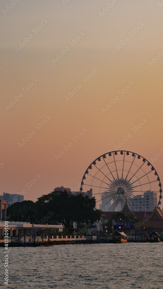 Landscape view of Farris Wheel at Chao Praya river in sunset, Bangkok, Thailand
