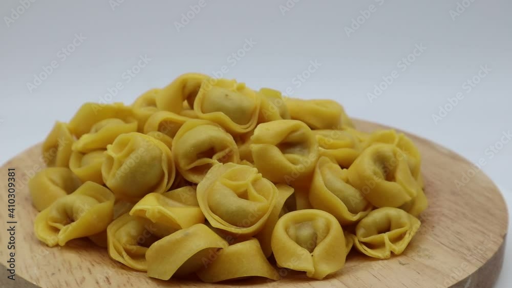 Raw tortellini on rotating display isolated on white. Traditional italian pasta
