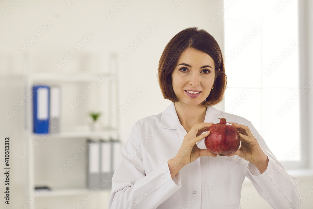 Diet and healthy food. Female nutritionist holding a pomegranate near the heart hinting at the health benefits of a healthy diet. Fresh fruits and healthy diet concept. Place for text. Diet and healthy food. Female nutritionist holding a pomegranate near the heart hinting at the health benefits of a healthy diet. Fresh fruits and healthy diet concept. Place for text.