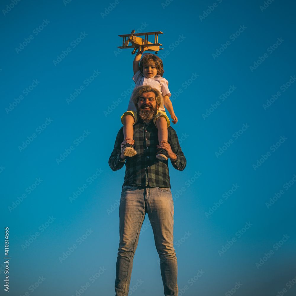 Father and son playing with wooden airplane. Boy sitting on fathers shoulders. Father and son playing with wooden airplane. Boy sitting on fathers shoulders.
