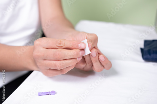 Close-up of the hands of a Latin woman doing a test at home with a glucometer to measure sugar levels as a prevention method to avoid suffering from diabetes