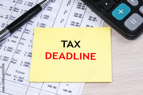 the tax deadline is written on a yellow sheet. A business document with numbers and a calculator. Business and financial concept.